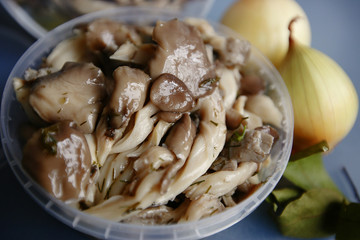 Marinated mushrooms with butter in a plastic container