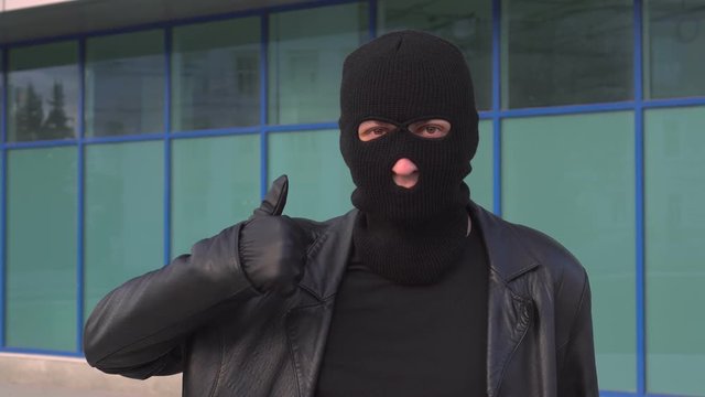 Criminal man thief or robber in mask shows thumb up.