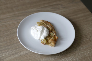 Slice of sweet rhubarb pie served with sweetened whipped cream. Selective focus. 