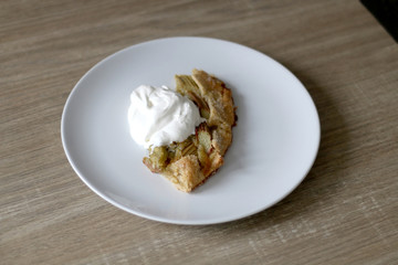 Slice of sweet rhubarb pie served with sweetened whipped cream. Selective focus. 