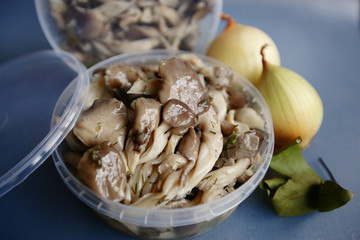 Marinated mushrooms with butter in a plastic container