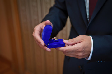 the groom holds wedding rings in hand