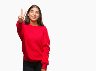 Obraz na płótnie Canvas Young beautiful arab woman wearing winter sweater over isolated background smiling looking to the camera showing fingers doing victory sign. Number two.