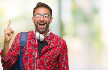 Adult hispanic student man wearing headphones and backpack over isolated background pointing finger...