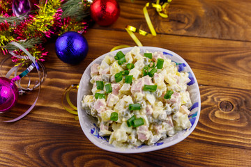 Traditional Russian festive salad Olivier and New Years decorations on wooden table