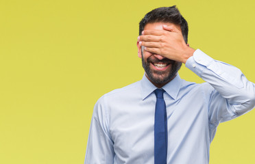 Adult hispanic business man over isolated background smiling and laughing with hand on face covering eyes for surprise. Blind concept.