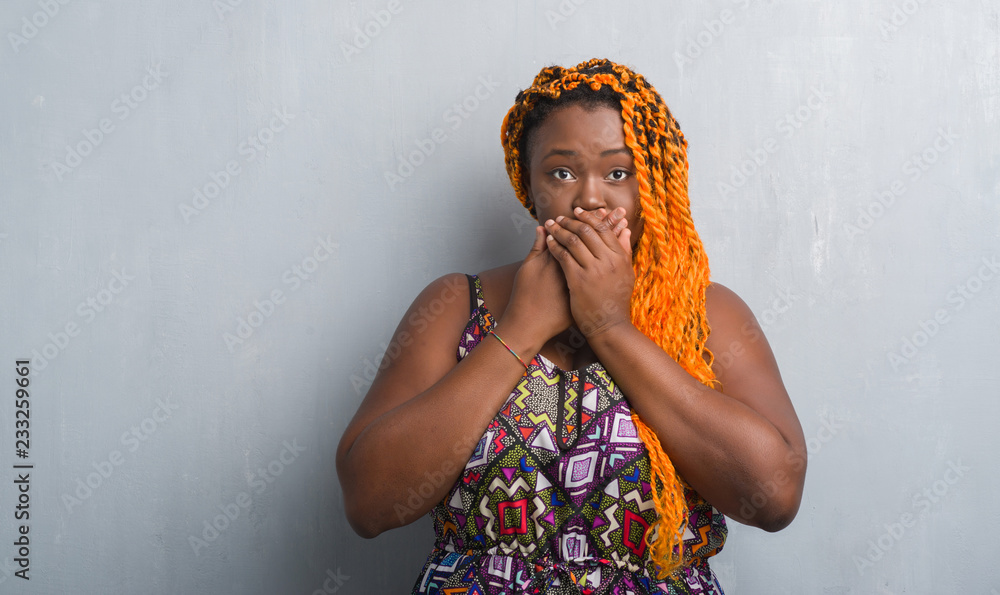 Canvas Prints Young african american woman over grey grunge wall wearing orange braids shocked covering mouth with hands for mistake. Secret concept.