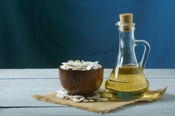 Pumpkin seeds in a cup and oil in a glass jug