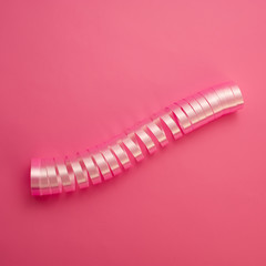 twisted ribbon lies on a pink background.