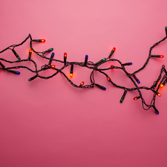 bulbs Christmas garland lie on a pink background.