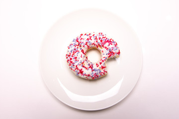 Overhead view of a donut on a white plate with a bite taken out