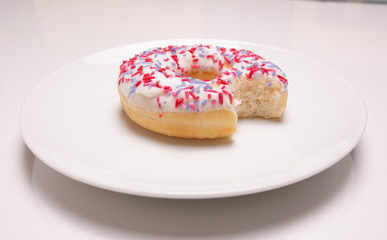 Obraz na płótnie Canvas donut on a white plate with a bite taken out on a white background
