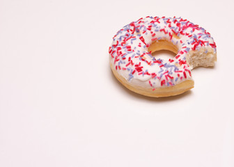 offset frosted donut with a bite taken out on a white background