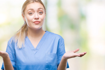 Young blonde surgeon doctor woman wearing medical uniform over isolated background clueless and...