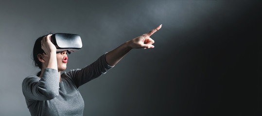 Young woman using a virtual reality headset on a gray background