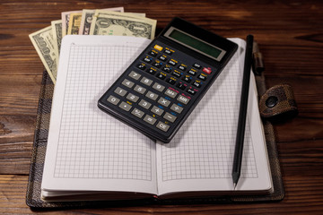 Notepad with dollars, pencil and calculator on wooden desk. Financial planning concept