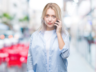 Young blonde woman talking using smarpthone over isolated background with a confident expression on smart face thinking serious