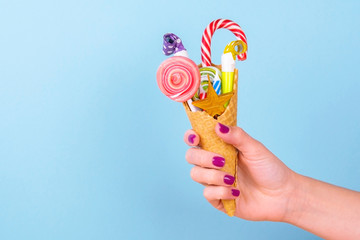 sweet tooth. female hand holding a waffle cone with sweets