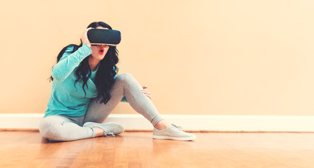 Young woman using a virtual reality headset against a big interior wall