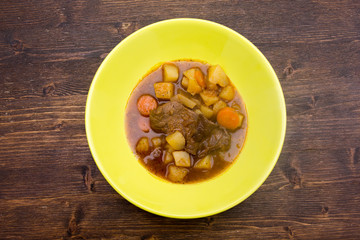 Stewed meat and vegetables on a wooden table seen from above