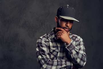 African-American bearded guy wearing a checkered shirt and cap