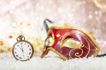 Carnival party. Minutes to midnight on an old watch, venetian mask, bokeh festive background