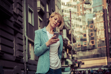 Stylish mid-age business woman texting on the street
