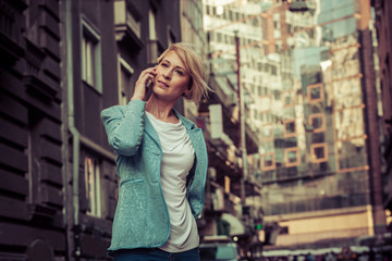 Confident mid-age woman talking on a cell phone in the street