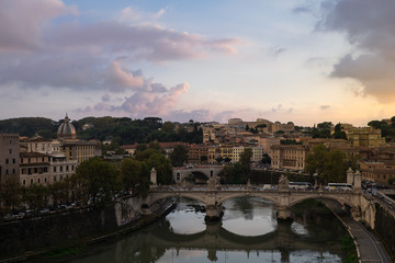 Fototapeta na wymiar View of busy traffic on bridge Vittorio Emanuele, Gianicolo hill with buildings and trees, located between Trastevere and Vatican. Shot from Castel San Angelo during sunset.