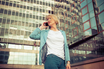 Beautiful business woman talking on a cell phone in front of the office building