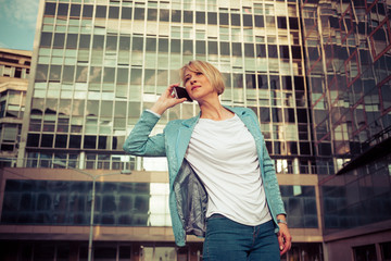 Fototapeta premium Beautiful business woman talking on a cell phone in front of the office building