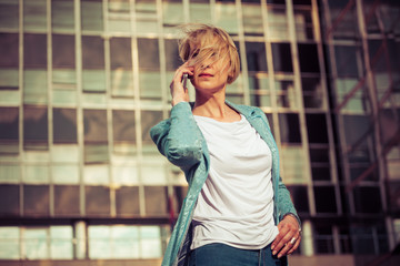 Fototapeta premium Beautiful business woman talking on a cell phone in front of the office building