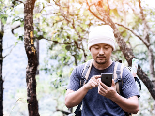 hiker with backpack checks map on phone to find directions in wilderness area