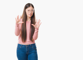 Fototapeta na wymiar Young Chinese woman over isolated background wearing glasses afraid and terrified with fear expression stop gesture with hands, shouting in shock. Panic concept.