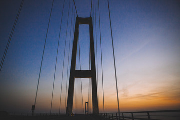 Travel by car over the bridge in Denmark. Motorway connecting Denmark and Germany. Sunset.