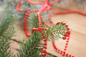 Fir branches and red necklace on wooden boards. Christmas decorations on wooden background. Christmas tree branches on natural background and copy space. Festive pattern, top view