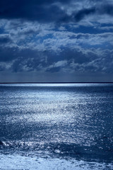 seascape of deep blue sea and sky lit by moonlight