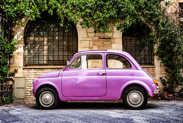 Pink Fiat 500 Oldtimer typical italian parking in front of a wall