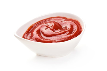 Tomato sauce or ketchup in a bowl, isolated on a white background. Close-up.