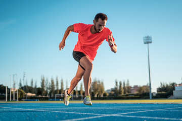 Young athlete man starting to run in a start position in a race. Start stride