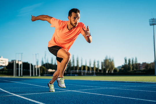 Young athlete man starting to run in a start position in a race. Start stride