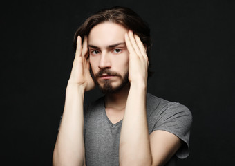 unhappy man touching his forehead over black background