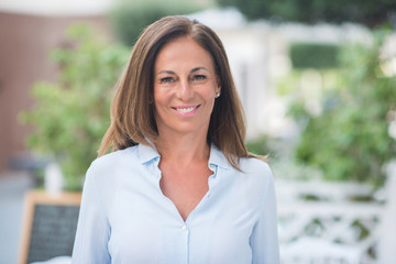 Naklejka premium Beautiful middle age hispanic woman standing with smile on face at the street. Walking through the city while smiling confident and cheerful on a sunny day.