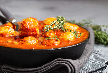 Spicy red beans, red bell pepper and meatball chili with thyme in the old frying pan. Grey concrete background. Copy space for text.