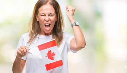 Middle age hispanic woman holding flag of Canada over isolated background annoyed and frustrated shouting with anger, crazy and yelling with raised hand, anger concept