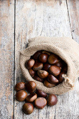 Fresh chestnuts in sack bag on the old wooden table