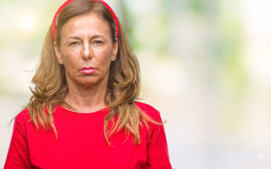 Middle age senior hispanic woman over isolated background with serious expression on face. Simple...