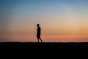silhouette of man running on the beach at sunset