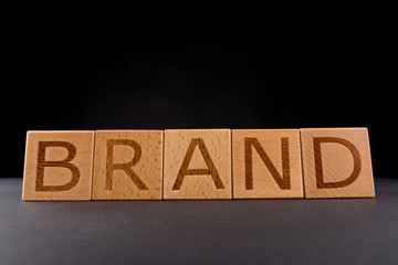 Wood cube block with word “BRAND” on Black Background. Brand building for success concept