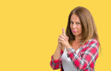 Fototapeta premium Beautiful middle age woman wearing over isolated background Holding symbolic gun with hand gesture, playing killing shooting weapons, angry face